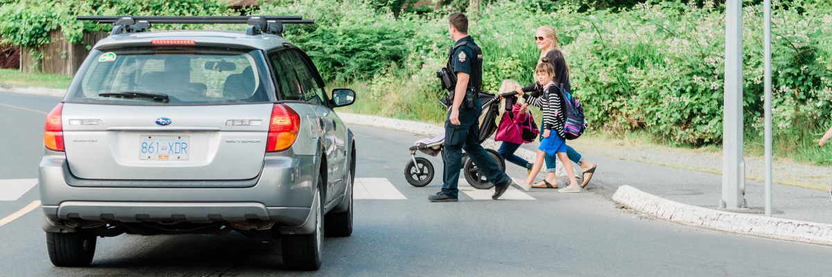 Family crossing the street in front of a stopped car